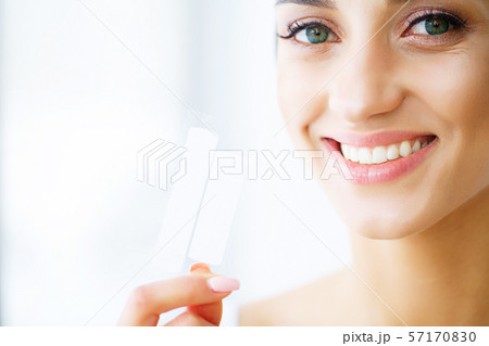 Woman Using Teeth Whitening Strip For Beautiful White Smile. High Resolution Image 57170830