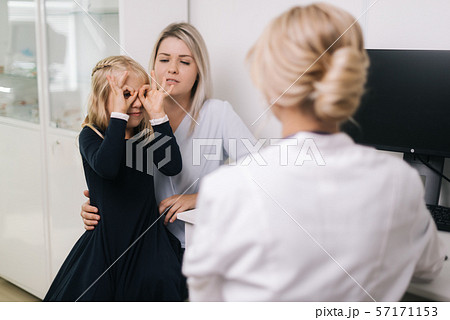 Cute funny kid girl with blond hair fooling around at a doctor on consultation Cute funny kid girl with blond hair fooling around at a doctor on consultation 57171153