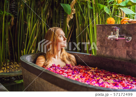 Attractive Young woman in bath with petals of tropical flowers and aroma oils. Spa treatments for Attractive Young woman in bath with petals of tropical flowers and aroma oils. Spa treatments for 57172499
