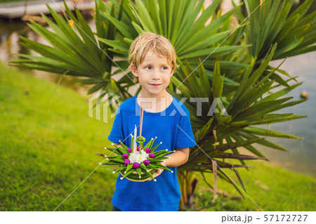 Boy tourist holds the Loy Krathong in her hands and is about to launch it into the water. Loy Boy tourist holds the Loy Krathong in her hands and is about to launch it into the water. Loy 57172727