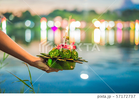 A female tourist holds the Loy Krathong in her hands and is about to launch it into the water. Loy 57172737