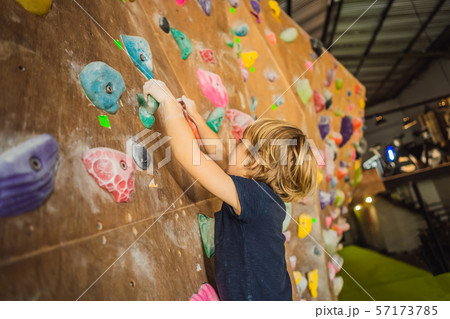 little boy climbing a rock wall in special boots. indoor little boy climbing a rock wall in special boots. indoor 57173785