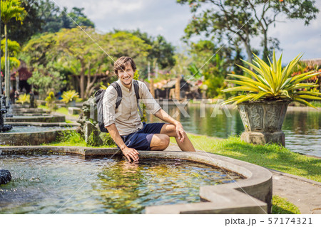 Young man tourist in Taman Tirtagangga, Water palace, Water park, Bali Indonesia Young man tourist in Taman Tirtagangga, Water palace, Water park, Bali Indonesia 57174321
