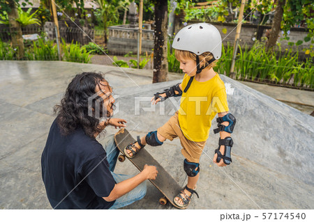 Athletic boy learns to skateboard with a trainer in a skate park. Children education, sports Athletic boy learns to skateboard with a trainer in a skate park. Children education, sports 57174540
