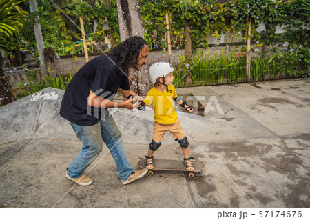 Athletic boy learns to skateboard with a trainer in a skate park. Children education, sports 57174676