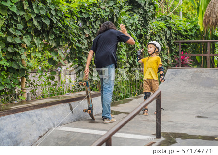 Athletic boy learns to skateboard with a trainer in a skate park. Children education, sports 57174771