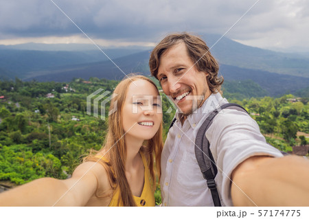Man and woman making selfie on background of Batur volcano and Agung mountain view at morning from Man and woman making selfie on background of Batur volcano and Agung mountain view at morning from 57174775