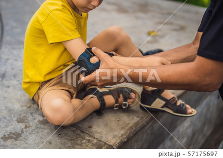 Trainer helps the boy to wear knee pads and armbands before training skate board Trainer helps the boy to wear knee pads and armbands before training skate board 57175697