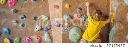 little boy climbing a rock wall in special boots. indoor BANNER, LONG FORMAT 57175977