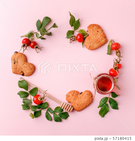 Ingredinets for winter fall autumn seasonal beverage tea party - fresh rose hip berries, honey, apple and heart-shaped biscuits. 57180415