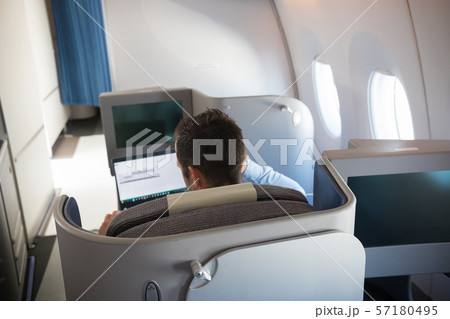 A man sitting in the business class cabin and working with his laptop A man sitting in the business class cabin and working with his laptop 57180495