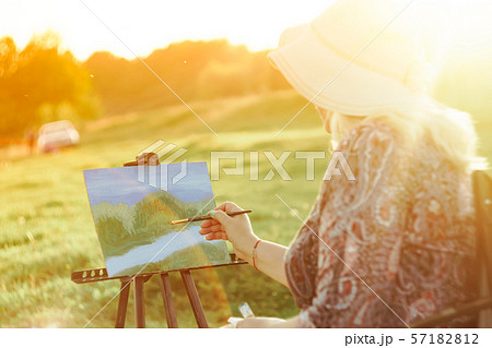 an elderly woman paints a picture in nature 57182812