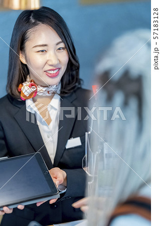 外国人旅行者にタブレットで交通情報を案内する笑顔の女性観光ガイド受付嬢 57183128