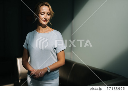 Portrait of attractive mature middle aged woman standing by the black couch Portrait of attractive mature middle aged woman standing by the black couch 57183996