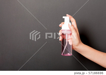 Female hand holding spray cream bottle of lotion 57186696