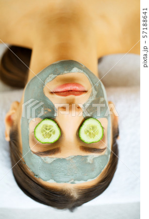 Woman with facial mask and cucumber slices in her hands Woman with facial mask and cucumber slices in her hands 57188641