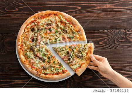 Hand holding slice of pizza with ham, pumpkin and Hand holding slice of pizza with ham, pumpkin and 57196112