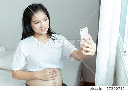 Cheerful pregnant young Asians woman sitting on 57200752