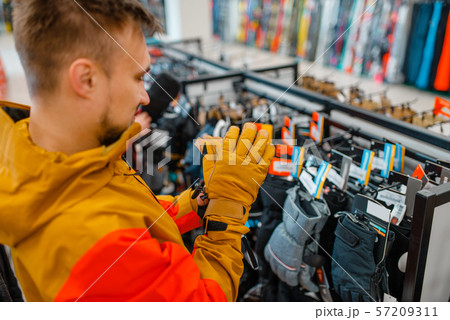 Man trying on gloves for ski or snowboarding Man trying on gloves for ski or snowboarding 57209311