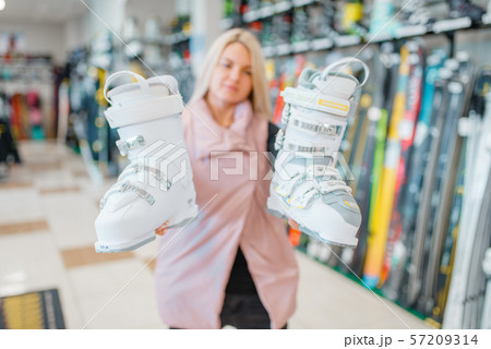 Woman shows ski or snowboarding boots, sports shop 57209314