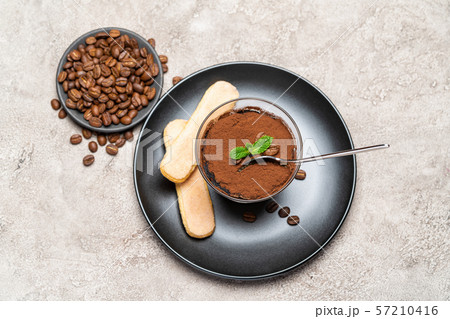 Portion of Classic tiramisu dessert in a glass cup on concrete background 57210416
