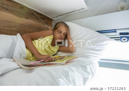 Girl fell asleep reading a magazine on the top 57221263