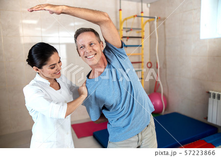 Smiling man is doing tilts to the side 57223866