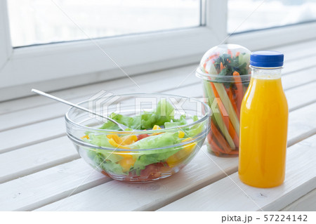 Bowl of green salad, raw vegetables and bottle of orange juice. Weight loss, diet and right 57224142