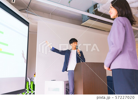 ビジネスイメージ:セミナーでプレゼンテーションをする部下を見守る女性マネージャー(管理職)のシーン ビジネスイメージ:セミナーでプレゼンテーションをする部下を見守る女性マネージャー(管理職)のシーン 57227020