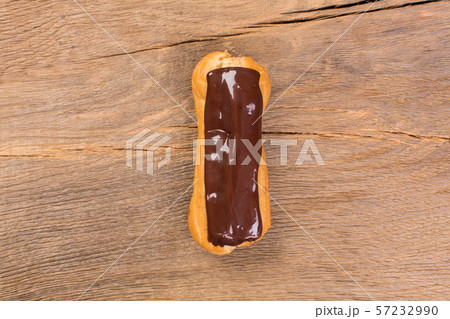 Dessert eclair with chocolate cream on wooden background. 57232990