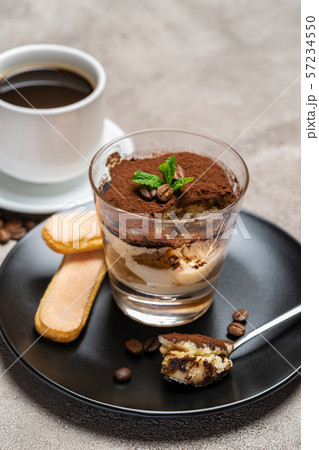 Portion of Classic tiramisu dessert in a glass cup and espresso coffee on concrete background Portion of Classic tiramisu dessert in a glass cup and espresso coffee on concrete background 57234550