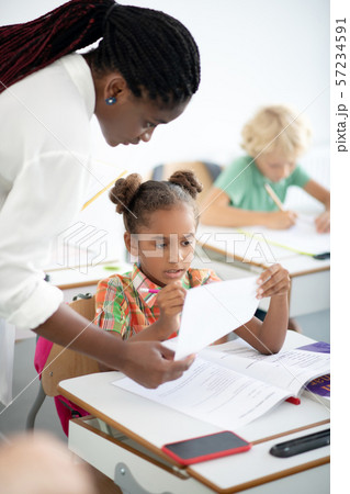 Dark-eyed girl correcting her mistakes after writing test 57234591