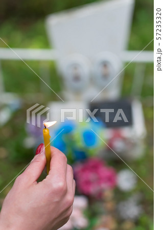 The flame of a wax candle in the hand of a people in the cemetery 57235320
