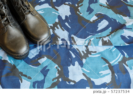 A pair of black army boots on fabric with blue A pair of black army boots on fabric with blue 57237534