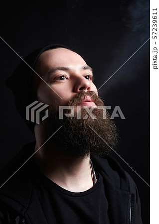 handsome bearded smoking man in Hat. 57239611