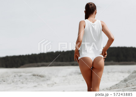 Sensual slim female in white swimsuit on beach 57243885