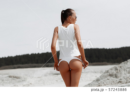 Sensual slim female in white swimsuit on beach 57243886