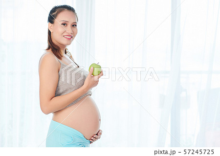 Pregnant woman eating green apple 57245725