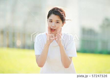 呼びかけるポーズをする白衣の女性 57247326