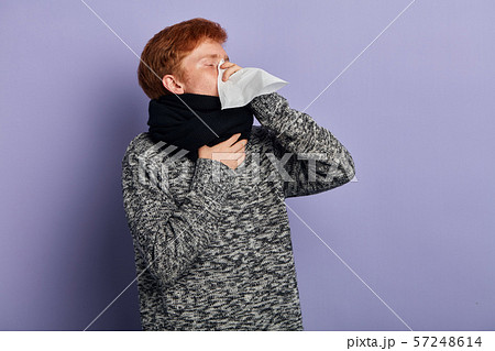 Unhealthy allergic student sneezes isolated over blue wall 57248614