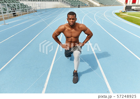 Handsome strong sportsman doing lunges, dressed in sportswear, outdoors 57248925