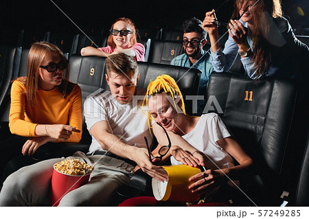 blonde guy splitting popcorn to his girlfriend's knees while watchin film 57249285