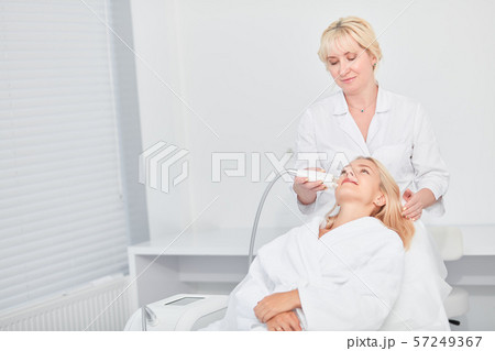 hardworking therapist lifting, cleansing the facial skin of patient. close up photo hardworking therapist lifting, cleansing the facial skin of patient. close up photo 57249367