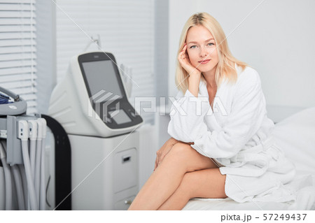 good looking positive girl with palm on her cheek sitting with crossed legs 57249437