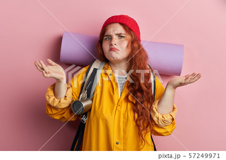 unhappy woman with clueless and confused expression shrugging her shoulders. 57249971