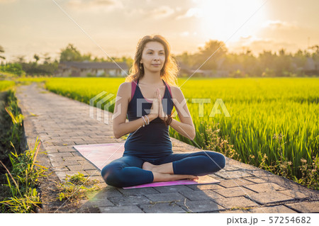 Young woman practice yoga outdoor in rice fields in the morning during wellness retreat in Bali 57254682
