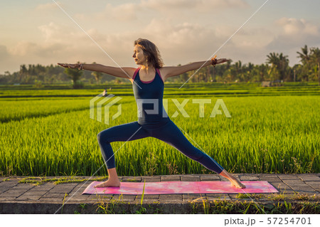 Young woman practice yoga outdoor in rice fields in the morning during wellness retreat in Bali 57254701