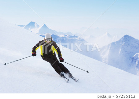 Alpine skier on piste running downhill 57255112