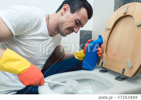Man is a bit disgusted cleaning the toilet Man is a bit disgusted cleaning the toilet 57263888