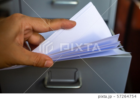 Woman's hand pick up white papers for write letter, Filing cabinet with open drawer, Grey silver metal colour, Administration and storage concept, closeup & Macro shot, Selective focus Woman's hand pick up white papers for write letter, Filing cabinet with open drawer, Grey silver metal colour, Administration and storage concept, closeup & Macro shot, Selective focus 57264754